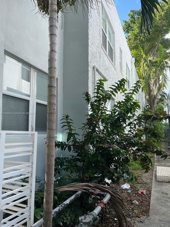 Side view of a multi-story residential building with white stucco walls and windows.