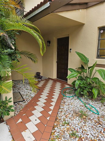 Front entrance of a house with a tiled pathway and plants.