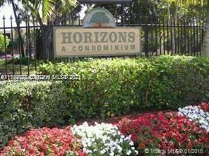 View of the entrance sign for Horizons A Condominium surrounded by flowers and greenery.