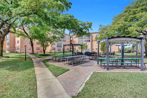Outdoor area with picnic tables and a building in the background.