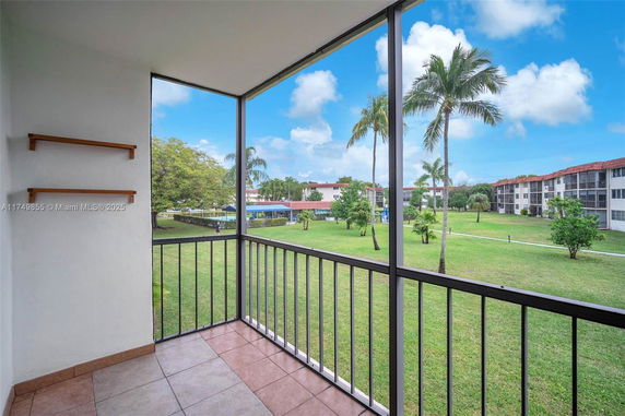 View from a balcony overlooking a grassy area and surrounding buildings.