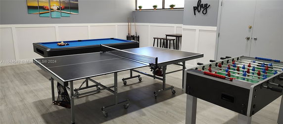 Indoor recreational area with a pool table, ping pong table, and foosball table.