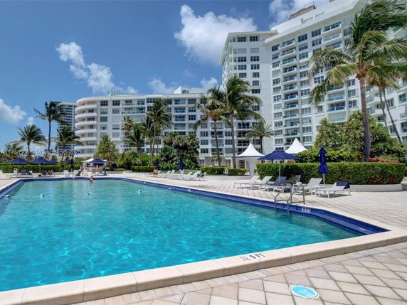 Swimming pool area in front of a multi-story residential building.