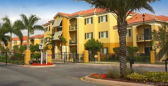Front view of a multi-story apartment building with balconies and gated entrance.