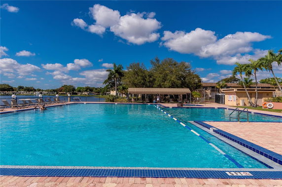 Outdoor swimming pool with lounge chairs and a lake in the background.
