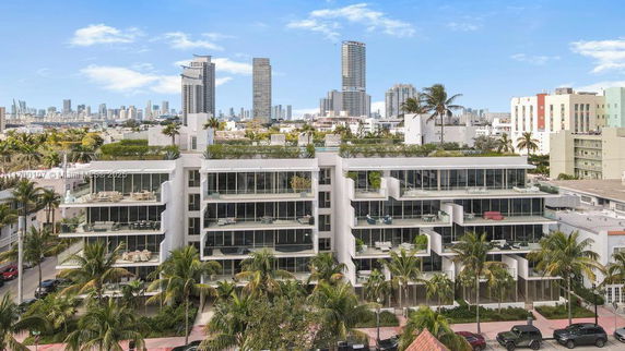 Front view of a modern multi-story apartment building with large glass balconies.