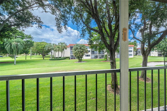 View from a balcony overlooking grassy areas and nearby residential buildings.
