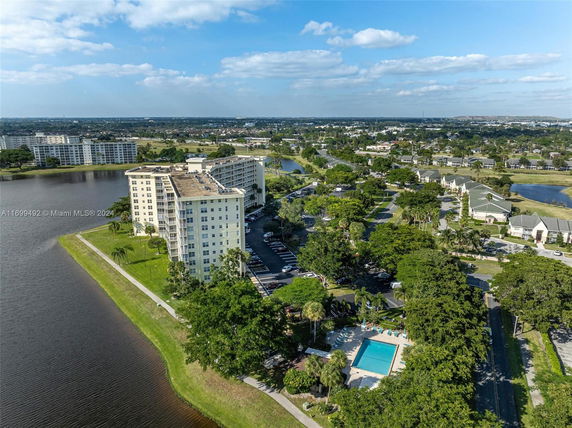 Panoramic view of an apartment complex at the edge of a lake, with surrounding residential areas.