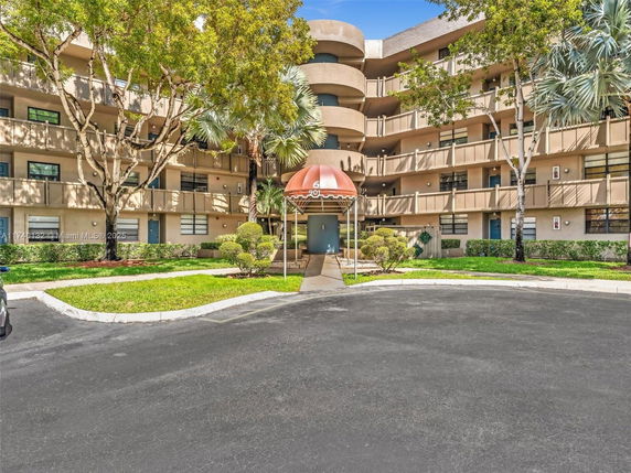 Front view of a multi-story residential building with balconies and an entrance canopy.