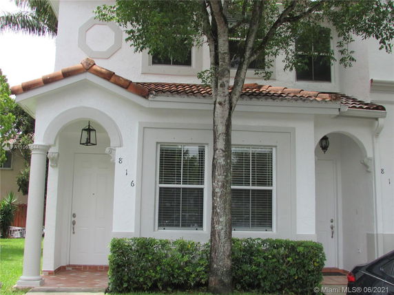 Front view of a two-story house with arched entrances and a tile roof.