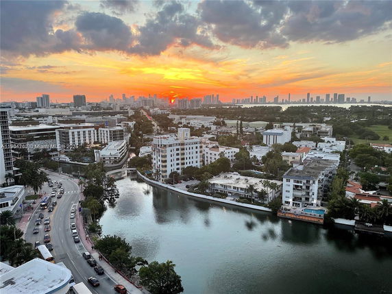 Panoramic view of a cityscape during sunset with a river and numerous buildings.