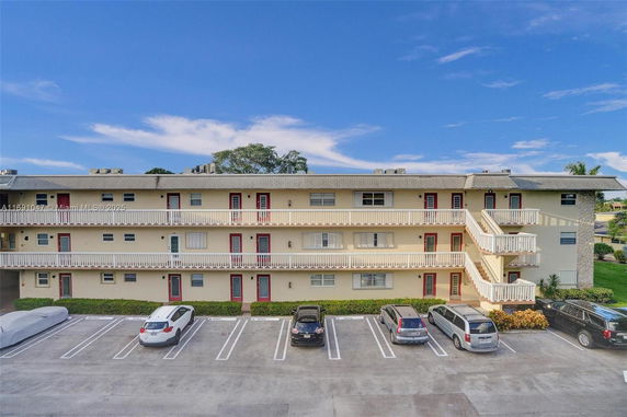 Front view of a three-story apartment building with a parking area.