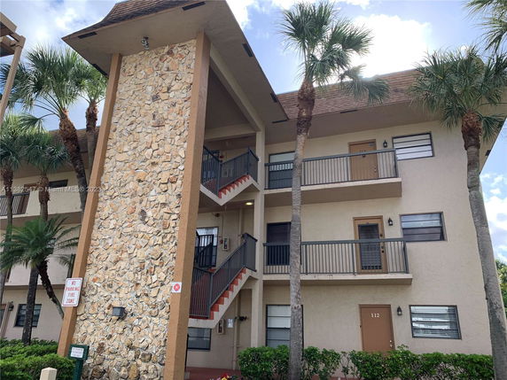 Front view of a multi-story building with balconies and stone detailing.