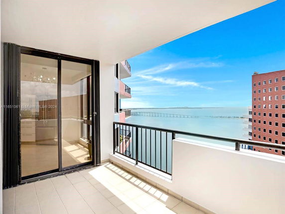 Balcony view overlooking the ocean and adjacent buildings.