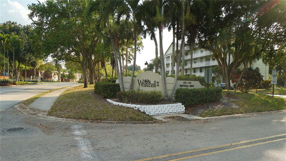 Street view of an entrance with a sign for Whitehall II and a multi-story residential building in the background.