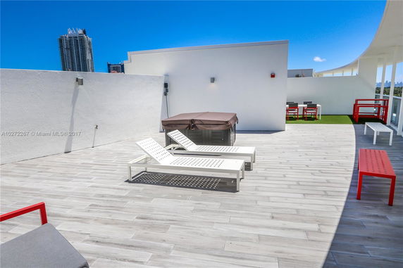 Rooftop space with lounge chairs, a jacuzzi, and dining area.