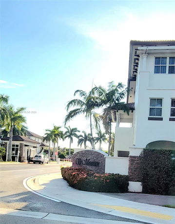 View of a residential building with palm trees and a street.