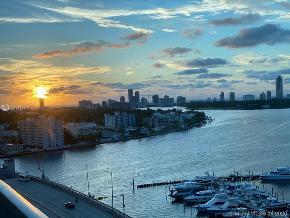 View of a waterfront with buildings and boats at sunset.