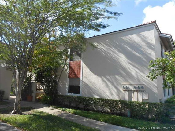Front view of a multi-story residential building with beige walls and red roofing tiles.