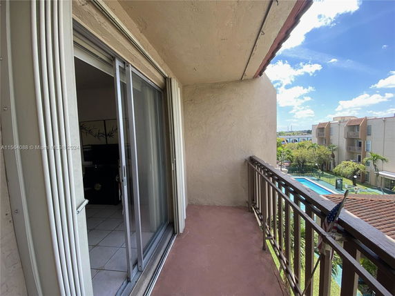 Balcony view overlooking a swimming pool and surrounding apartment buildings.