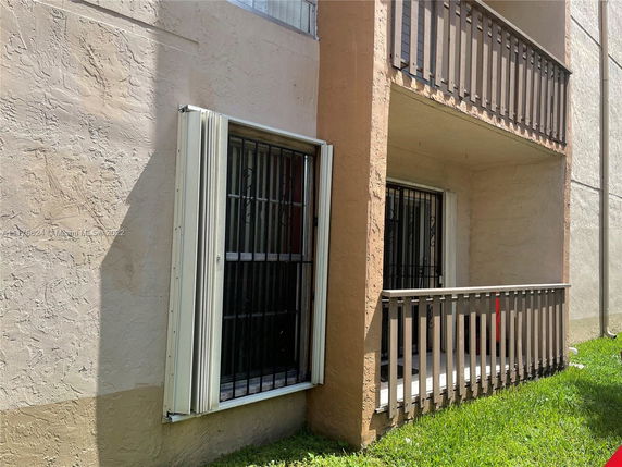 Front view of a building with a small balcony and security bars on windows.