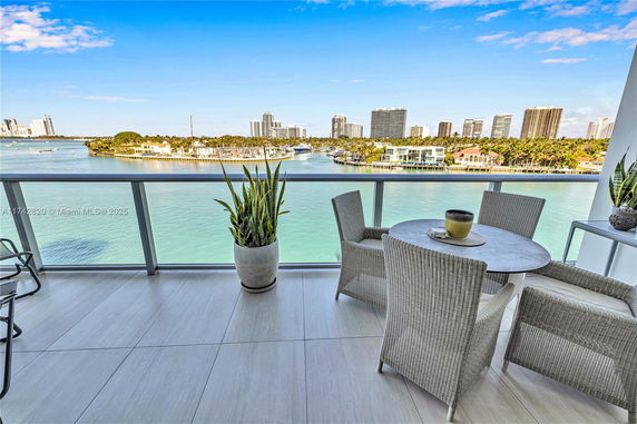 Balcony view with outdoor seating overlooking a body of water and cityscape.