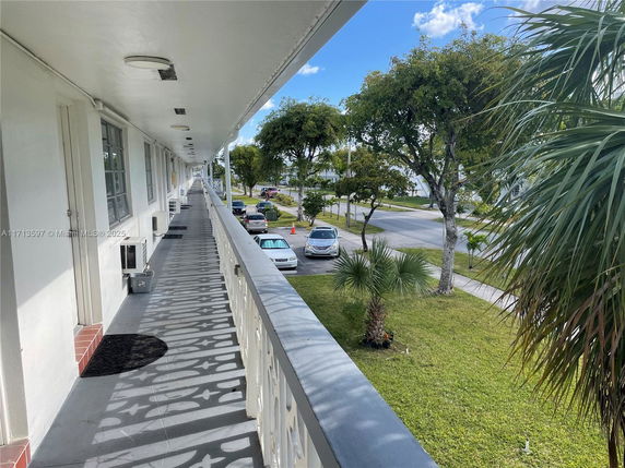 View from a balcony showing a parking area and surrounding greenery.