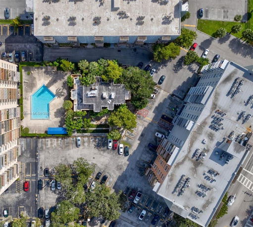 Aerial view of multi-story buildings with a blue swimming pool and parking lots.