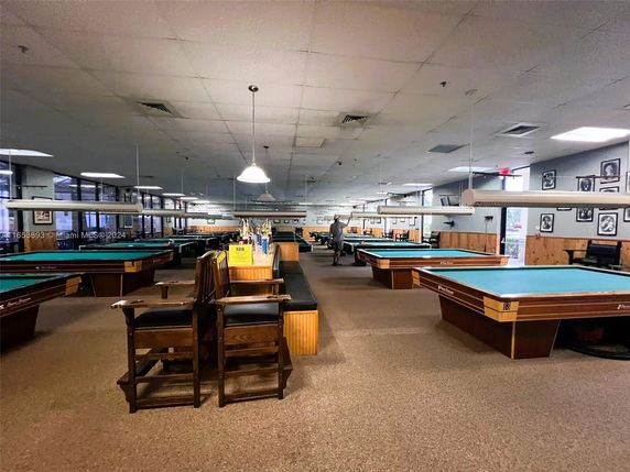 Interior view of a room with several pool tables and seating area.