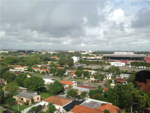 Wide view of suburban area with houses and trees, and a distant large building.