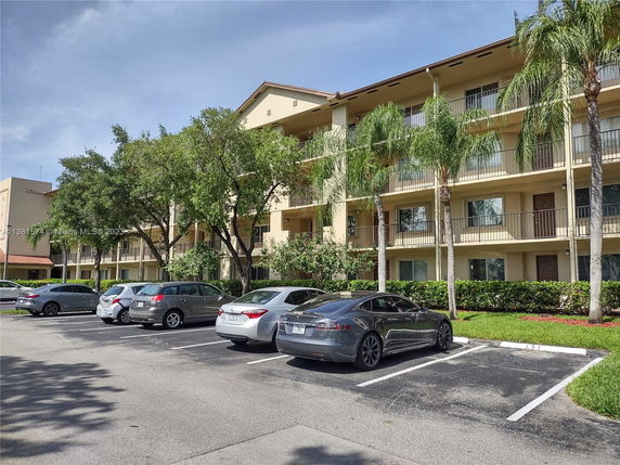 Outdoor parking area in front of a multi-story building with balconies.
