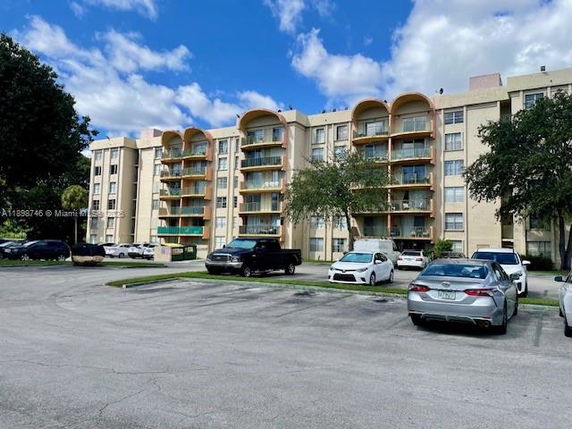 Front view of a multi-story residential building with balconies and parking area.