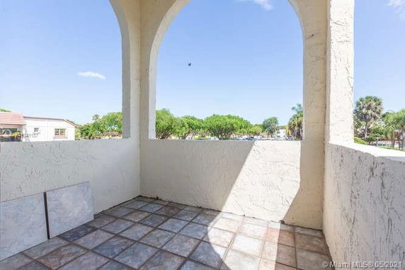 Balcony view with tiled flooring and archways overlooking greenery.