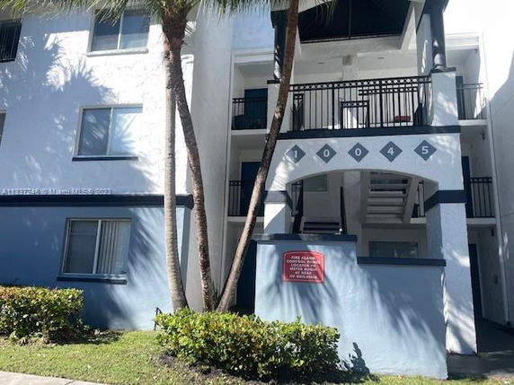 Front view of a multi-story residential building with balconies and a number sign.