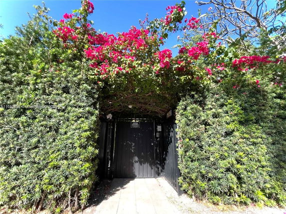 Entrance gate surrounded by lush greenery and flowering plants.
