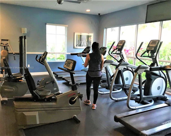 Indoor gym with exercise machines and a person working out.
