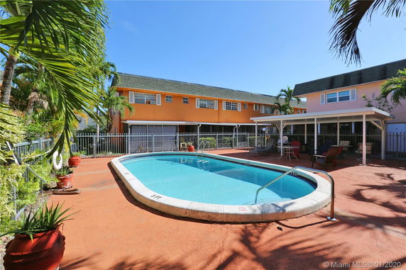 Outdoor swimming pool area with adjacent buildings and surrounding greenery.