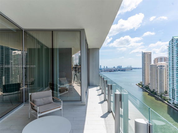 Balcony view overlooking cityscape and water with high-rise buildings.
