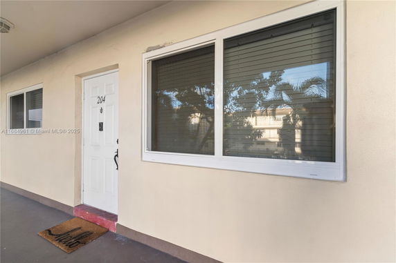 Front view of an apartment door with a large window and welcome mat.