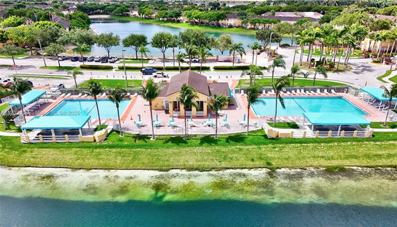 Aerial view of a swimming pool area with surrounding buildings and a lake.