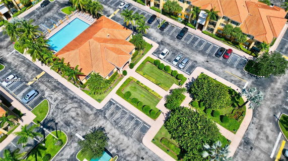 Aerial view of a complex with a central swimming pool, red-roofed structure, and parking area.