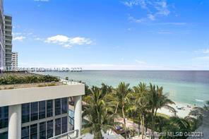 Building next to a beach with a clear view of the ocean and palm trees.