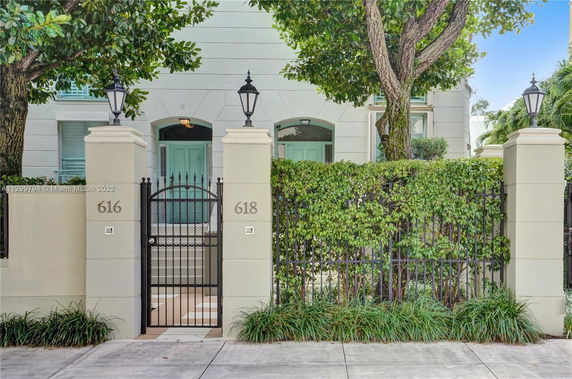 Front view of a residential building with a gated entrance and prominent light fixtures.