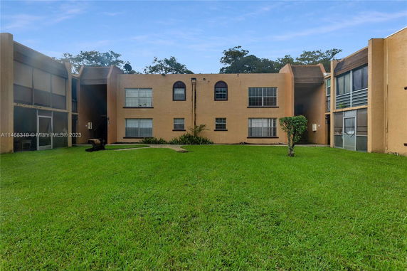 Front view of a two-story apartment complex with beige walls and multiple windows.