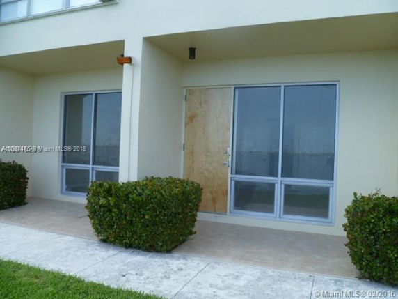 Front view of a building with large glass windows and a boarded-up door.