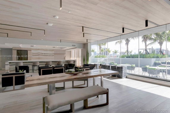 Interior view of a modern clubhouse with seating areas and large windows.