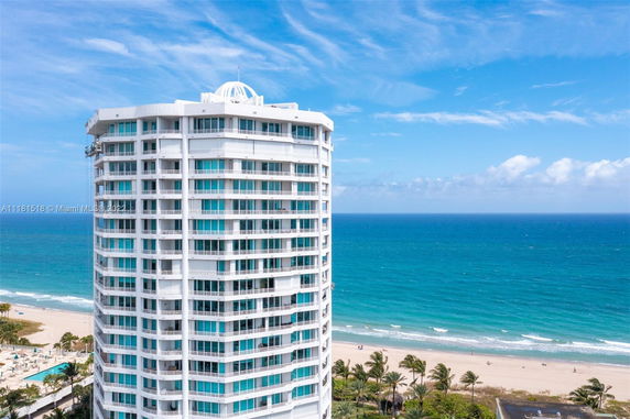 Front view of a multi-story beachfront building with balconies overlooking the ocean.