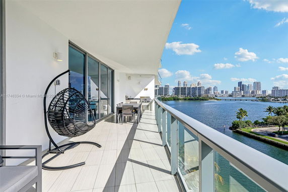 Wide angle view from a building balcony showing a cityscape with high-rise buildings and a body of water.