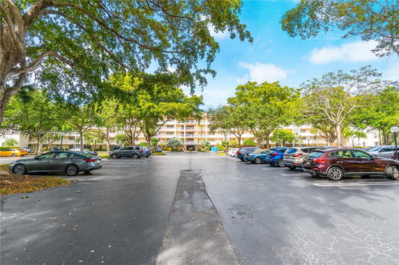 Front view of a multi-story building with a parking lot filled with cars.