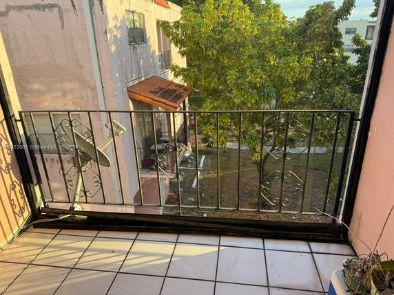 View from a balcony with a railing overlooking neighboring buildings and trees.